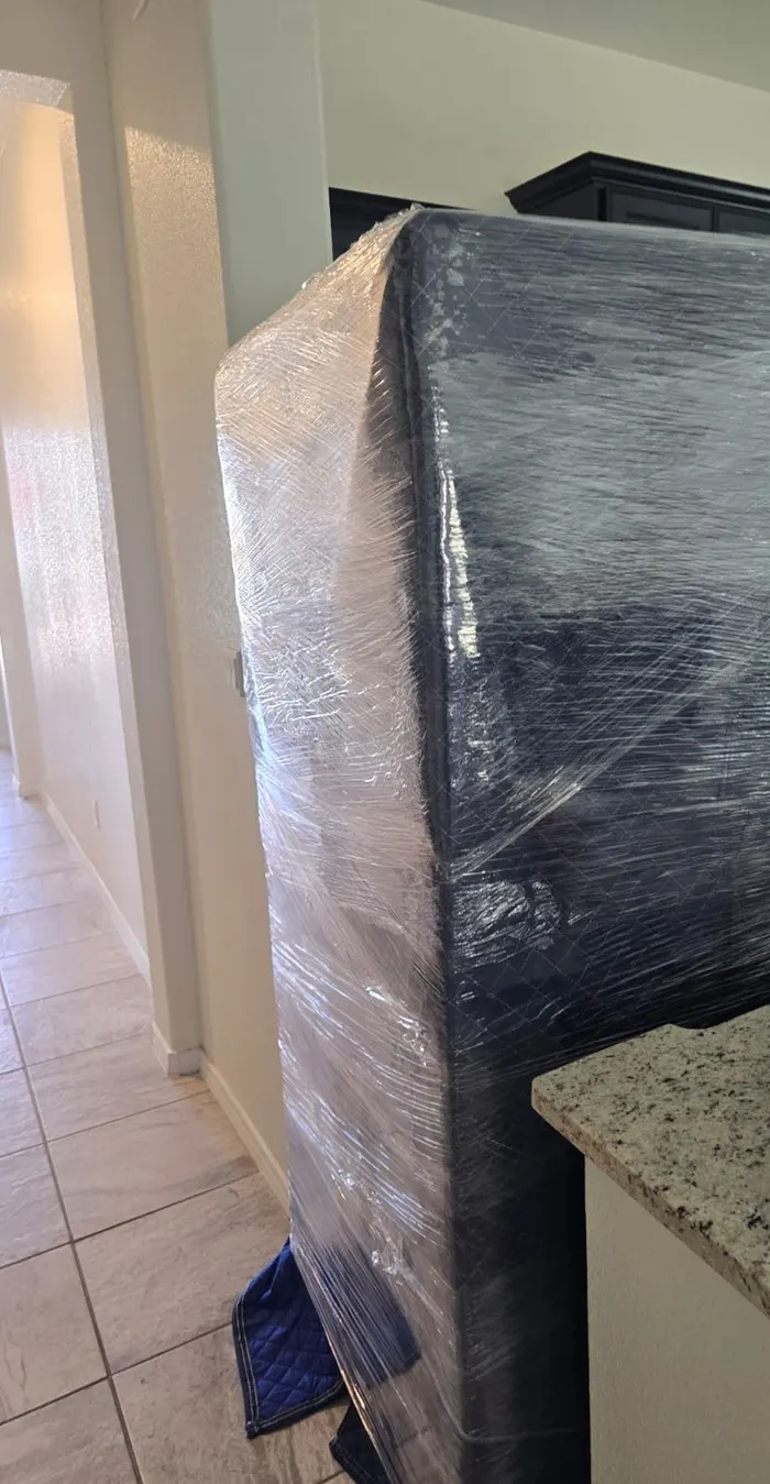 Mueble alto envuelto en cobija azul y plástico, listo para mudanza