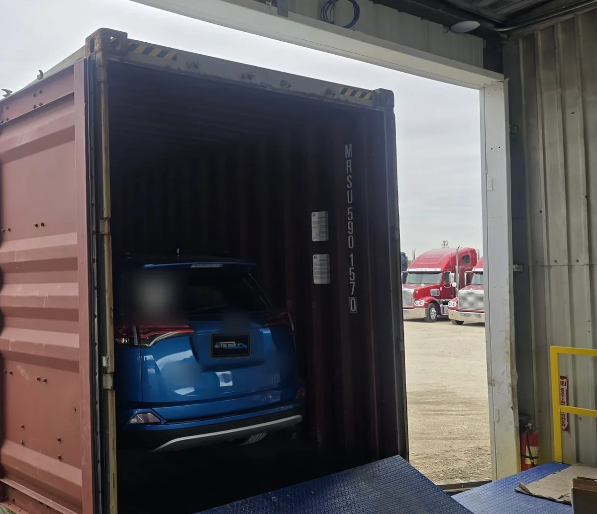 SUV azul cargado dentro de un contenedor en el muelle de carga, listo para viajar a El Salvador